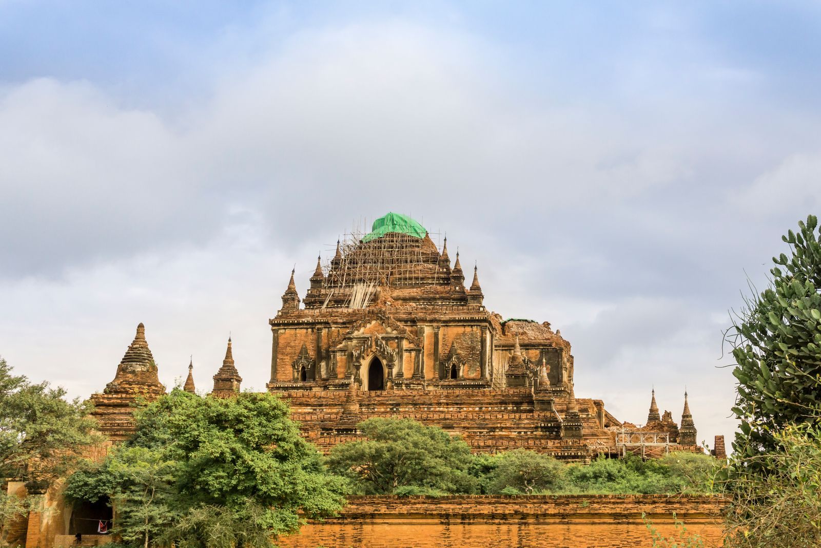 Htilominlo Temple in Bagan rising above trees under a cloudy sky, a highlight of any Bagan river cruise