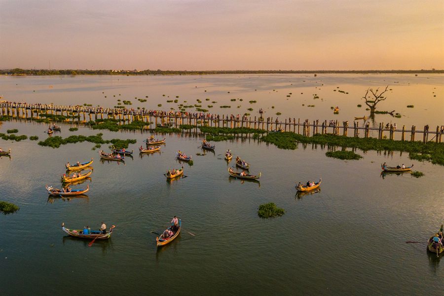 Small boats on Taungthaman Lake beside the U Bein Bridge at sunset